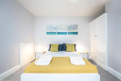 a bedroom with a large bed with yellow and blue pillows at Bedzzz - Booklovers Dream in Preston