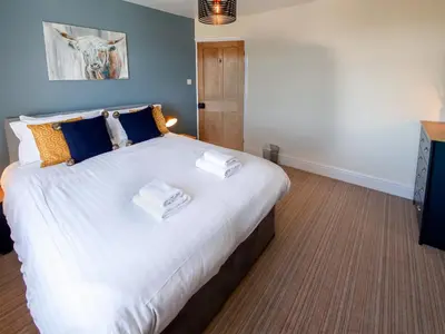 a bedroom with a large bed with towels on it at Dunmail House in Grange Over Sands