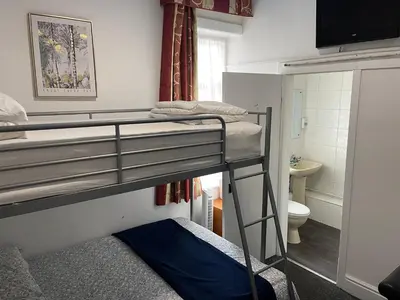a room with two bunk beds and a bathroom at Backpackers Blackpool Hotel & Suites in Blackpool