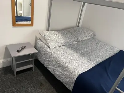 a bedroom with a bed with a night stand and a mirror at Backpackers Blackpool Hotel & Suites in Blackpool