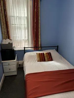 a small bedroom with a bed and a window at Backpackers Blackpool Hotel & Suites in Blackpool