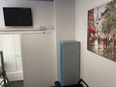 a tv sitting on a shelf next to a wall at Backpackers Blackpool Hotel & Suites in Blackpool