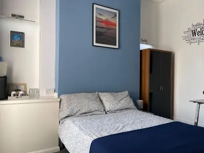 a bedroom with a bed and a blue wall at Backpackers Blackpool Hotel & Suites in Blackpool