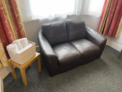 a brown leather couch in a room with a table at Backpackers Blackpool Hotel & Suites in Blackpool