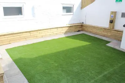 a patio with green grass on the side of a building at Backpackers Blackpool Hotel & Suites in Blackpool