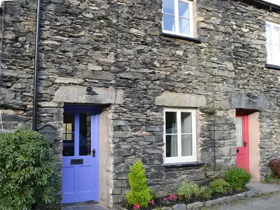 a stone house with blue and red doors at Coopers Cottage in Haverthwaite