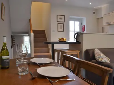 a dining room table with a bottle of wine on it at Coopers Cottage in Haverthwaite