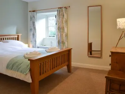 a bedroom with a bed and a mirror and a window at Coopers Cottage in Haverthwaite