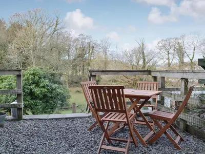 a wooden table and two chairs sitting next to a fence at Coopers Cottage in Haverthwaite
