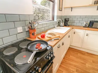a kitchen with a stove with a frying pan on it at The Stopping Point- Exceptional Cumbrian Cottage in Flookburgh