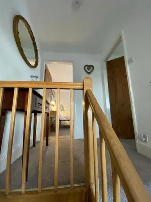 a stairway with a wooden rail and a mirror at The Stopping Point- Exceptional Cumbrian Cottage in Flookburgh