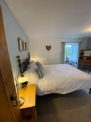 a bedroom with a bed and a table and a window at The Stopping Point- Exceptional Cumbrian Cottage in Flookburgh