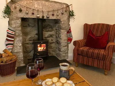 a living room with a fireplace with two glasses of wine at The Stopping Point- Exceptional Cumbrian Cottage in Flookburgh