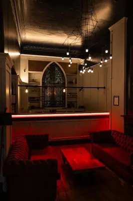 a bar with two red couches in a room at Malacuna Liverpool in Liverpool