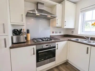 a kitchen with white cabinets and a stove top oven at Shore View in Grange Over Sands