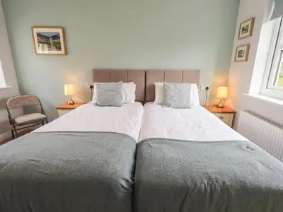 two beds in a bedroom with two lamps on tables at Shore View in Grange Over Sands
