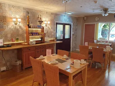 a dining room with tables and chairs and a kitchen at Corona Blackpool in Blackpool