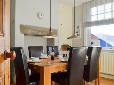 a dining room with a wooden table and black chairs at Lythdene in Grange Over Sands