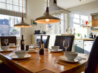 a wooden table with wine bottles and glasses on it at Lythdene in Grange Over Sands
