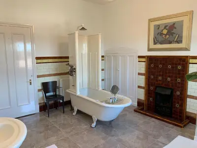 a bathroom with a white tub and a fireplace at Aberley House in Liverpool