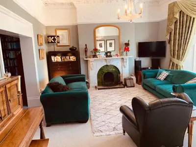 a living room with two green couches and a fireplace at Aberley House in Liverpool