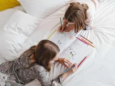 two young girls laying in bed with drawings and pens at ibis Liverpool Centre Albert Dock – Liverpool One in Liverpool