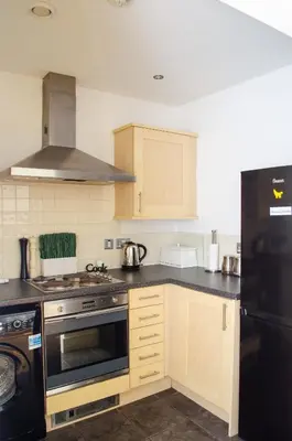 a kitchen with wooden cabinets and a black refrigerator at Ropewalks Apartments by Happy Days in Liverpool