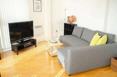 a living room with a gray couch and a flat screen tv at Ropewalks Apartments by Happy Days in Liverpool