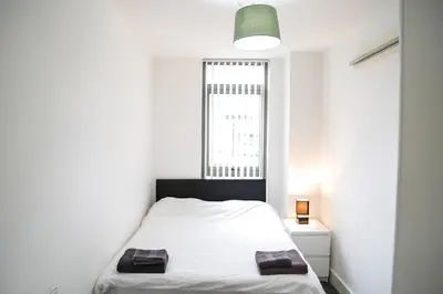 a small white bedroom with a bed and a window at Ropewalks Apartments by Happy Days in Liverpool