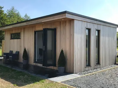 a small wooden shed with glass doors and chairs at Parkknott Retreat Luxury Lodge with Private Hot Tub in Askam in Furness