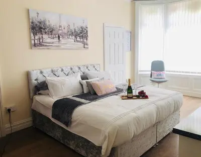 a bedroom with a bed with a bottle of wine on it at The Winter Garden Suites in Blackpool