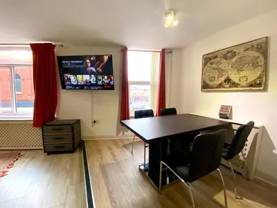 a room with a table and a tv on the wall at Simpson Beach View Apartments by Blackpool Service Apartments in Blackpool
