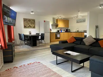 a living room with a couch and a table and a kitchen at Simpson Beach View Apartments by Blackpool Service Apartments in Blackpool