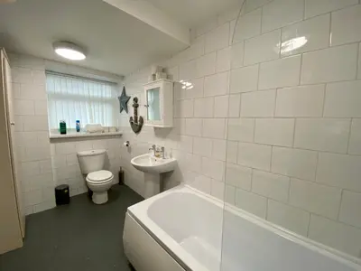 a bathroom with a tub and a toilet and a sink at Simpson Beach View Apartments by Blackpool Service Apartments in Blackpool
