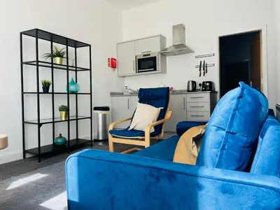 a living room with a blue couch and a kitchen at The Seacroft in Southport