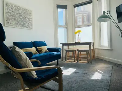 a living room with a blue couch and a table at The Seacroft in Southport