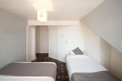 a small room with two beds in a attic at MyRoomz Hollingdales Hotel in Blackpool