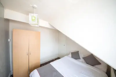 a small bedroom with a bed and a staircase at MyRoomz Hollingdales Hotel in Blackpool