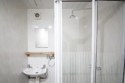 a white bathroom with a shower and a sink at MyRoomz Hollingdales Hotel in Blackpool
