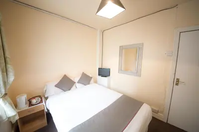 a small bedroom with a bed and a window at MyRoomz Hollingdales Hotel in Blackpool