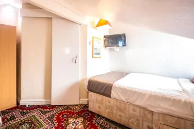 a hotel room with two beds and a tv at MyRoomz Hollingdales Hotel in Blackpool