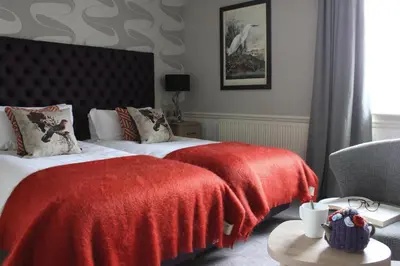 a hotel room with two beds and a red blanket at The Millstone, Mellor in Blackburn