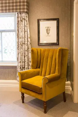 a yellow chair in a room with a window at The Millstone, Mellor in Blackburn