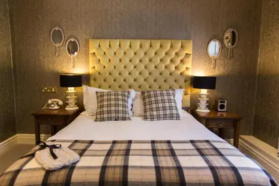 a bedroom with a large bed with a plaid blanket at The Millstone, Mellor in Blackburn