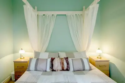 a bedroom with a bed with white curtains and two lamps at Cottage - Sleeps 5 - Hot Tub - Garden - Parking in Lancaster