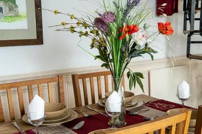 a table with a vase of flowers on it at Cottage - Sleeps 5 - Hot Tub - Garden - Parking in Lancaster