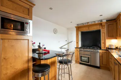 a kitchen with wooden cabinets and a counter with stools at Cottage - Sleeps 5 - Hot Tub - Garden - Parking in Lancaster