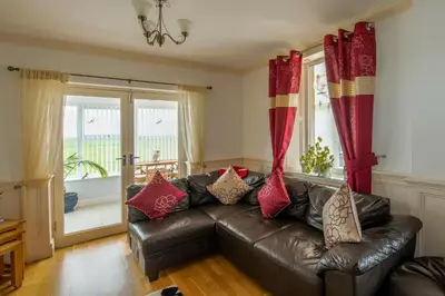 a living room with a leather couch with red curtains at Cottage - Sleeps 5 - Hot Tub - Garden - Parking in Lancaster