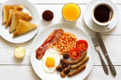 a plate of breakfast food with eggs sausage beans and toast at The Hotel at Mill Farm in Kirkham