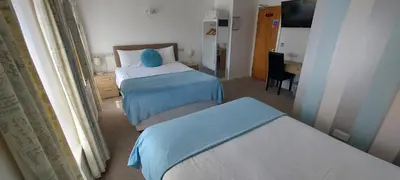 a hotel room with two beds and a desk at Four Seasons Guest House in Blackpool